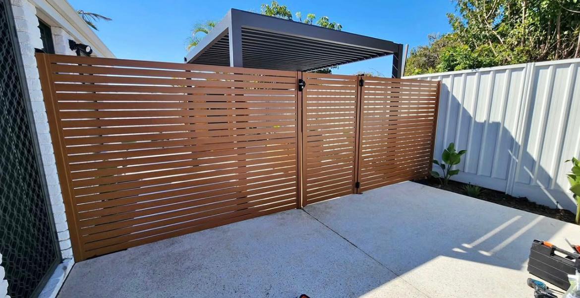 Timber-tone horizontal slat fence and gate across a concrete side yard