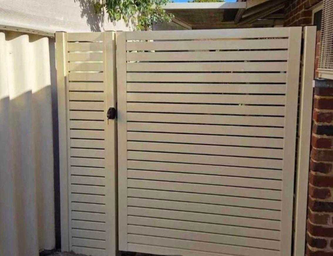 Cream horizontal slat side gate beside a brick house