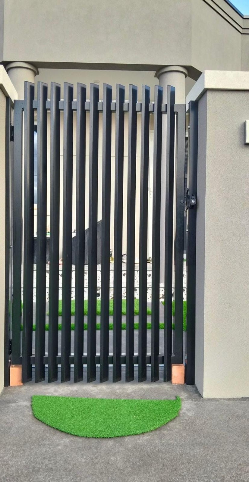 Black vertical blade pedestrian gate set into a rendered pillar entrance